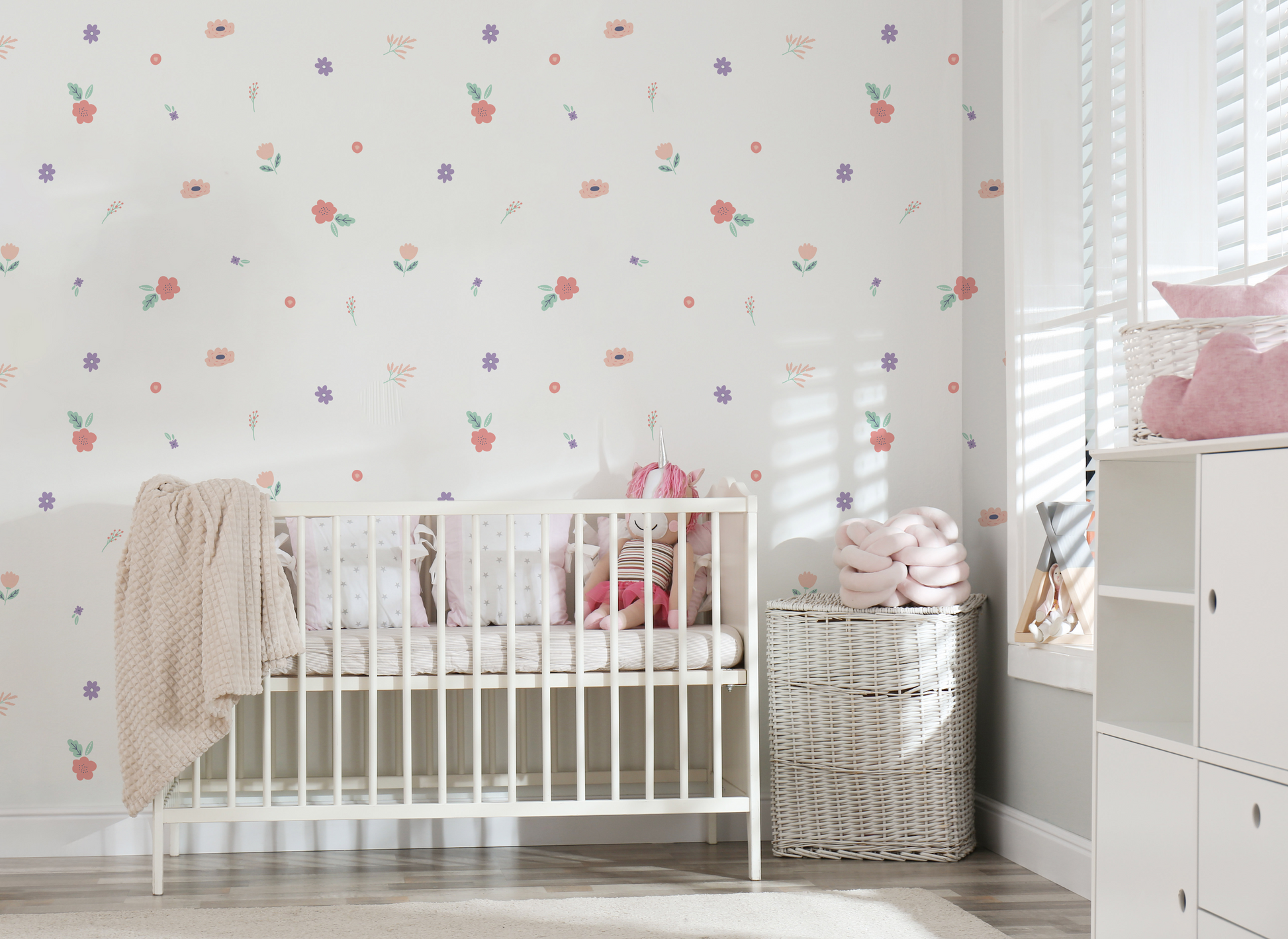 a baby's room with a white crib and a flower wallpaper