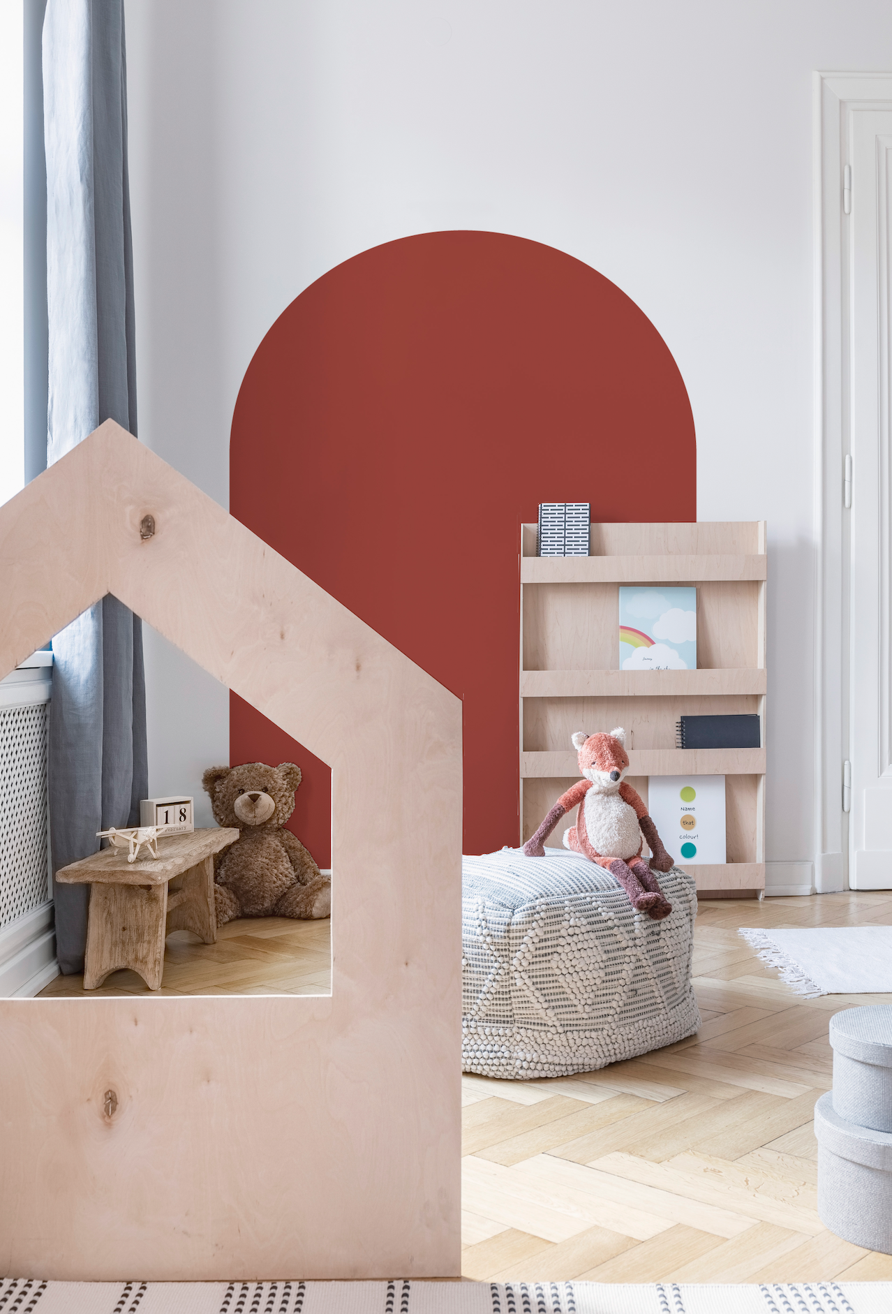 a child's room with a red wall and a wooden doll house