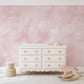 a baby's room with pink walls and a white dresser