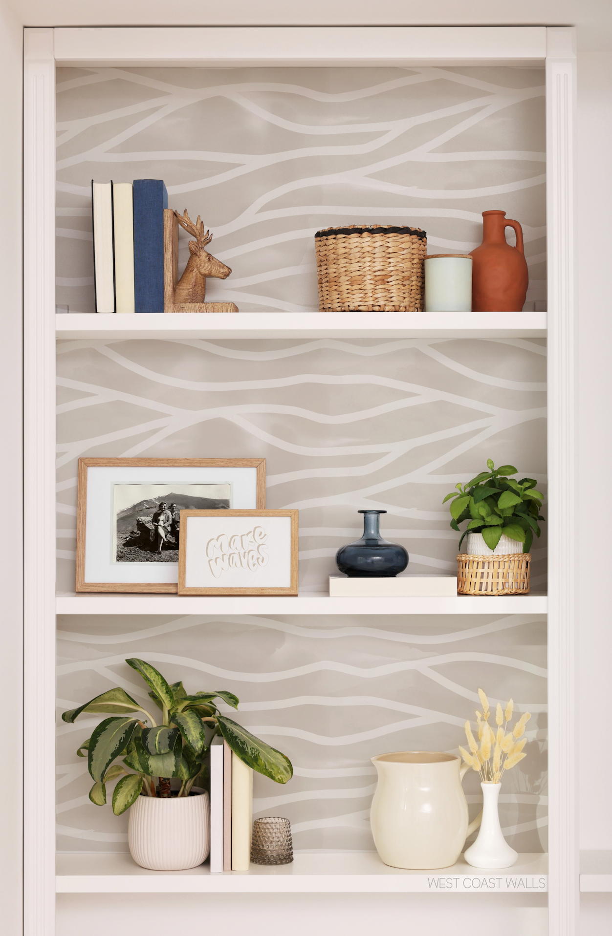 a white book shelf filled with books and plants