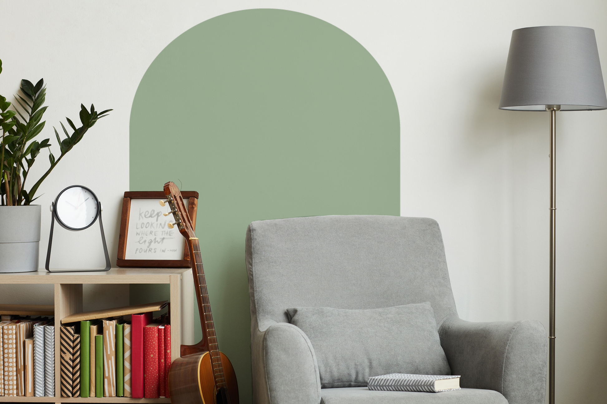 a living room with a gray chair and a green wall