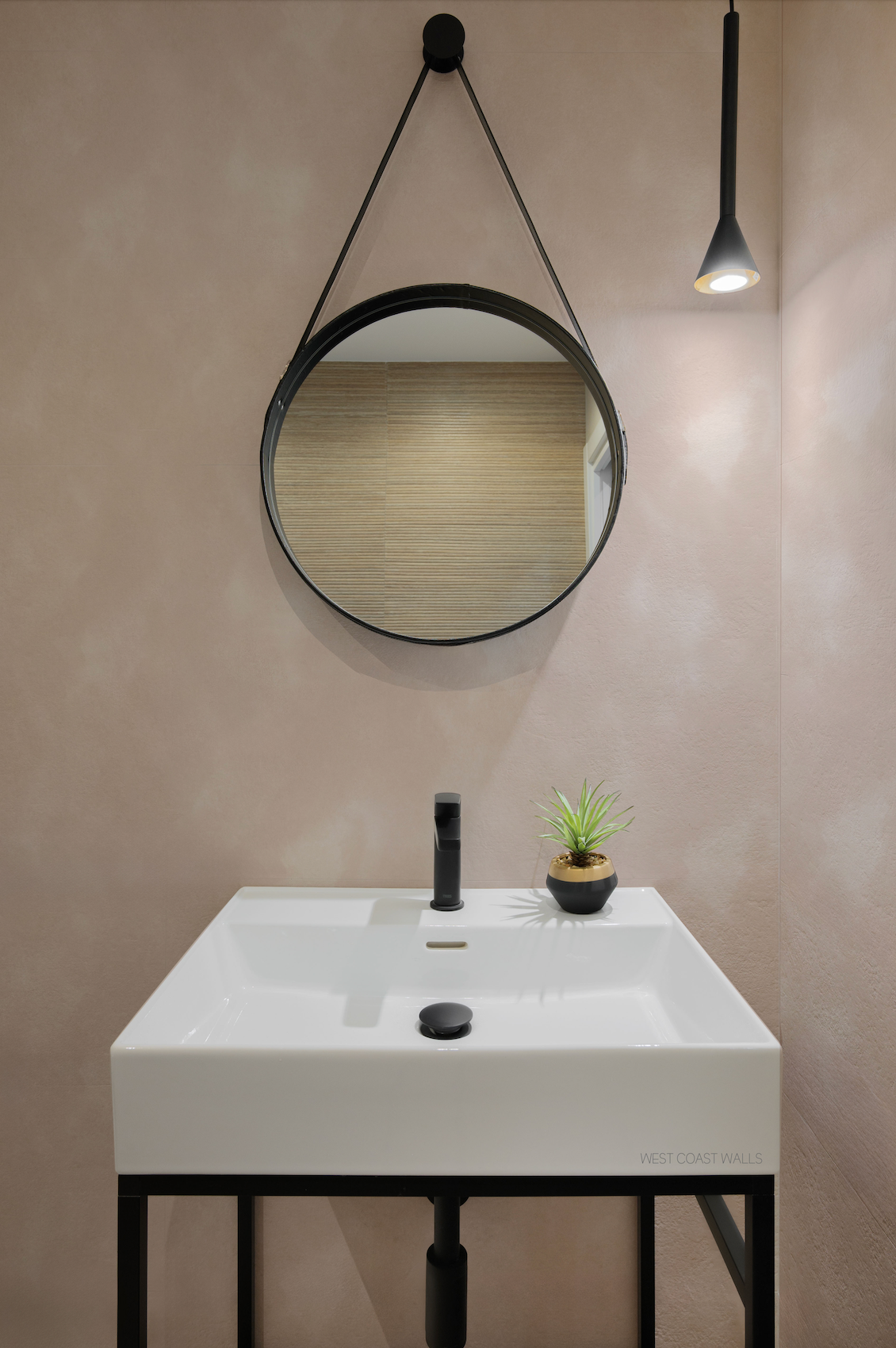 a white sink sitting under a round mirror